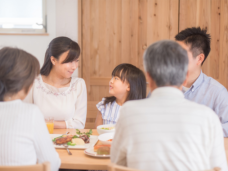 家族でご飯を食べながら会話ヲ楽しんでいる写真